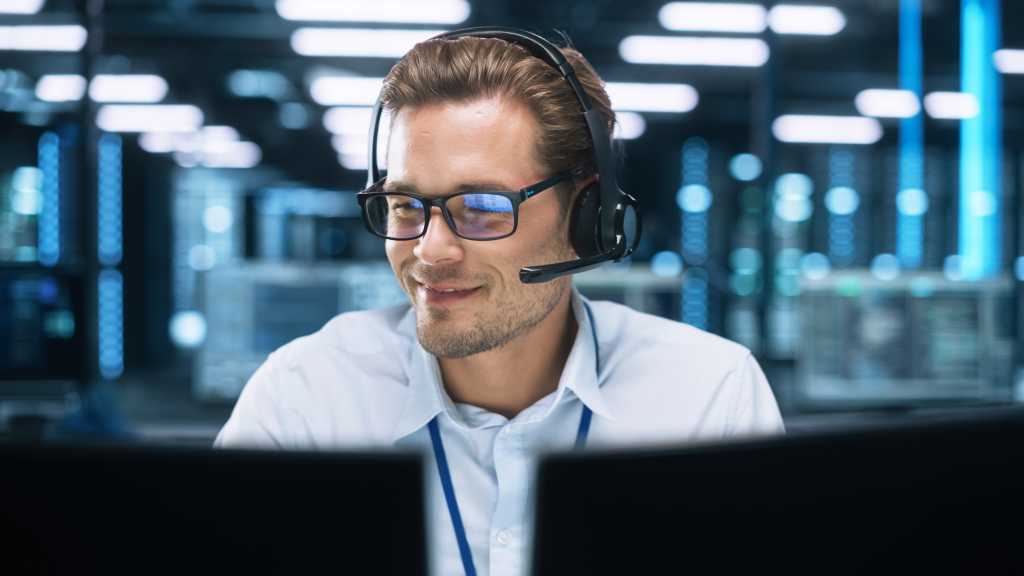 Concentrated Male Customer Support Agent Receptionist wear Headset Consult Online Client Looking at Computer Screen, Helpline Operator Secretary Make Conference Video Call