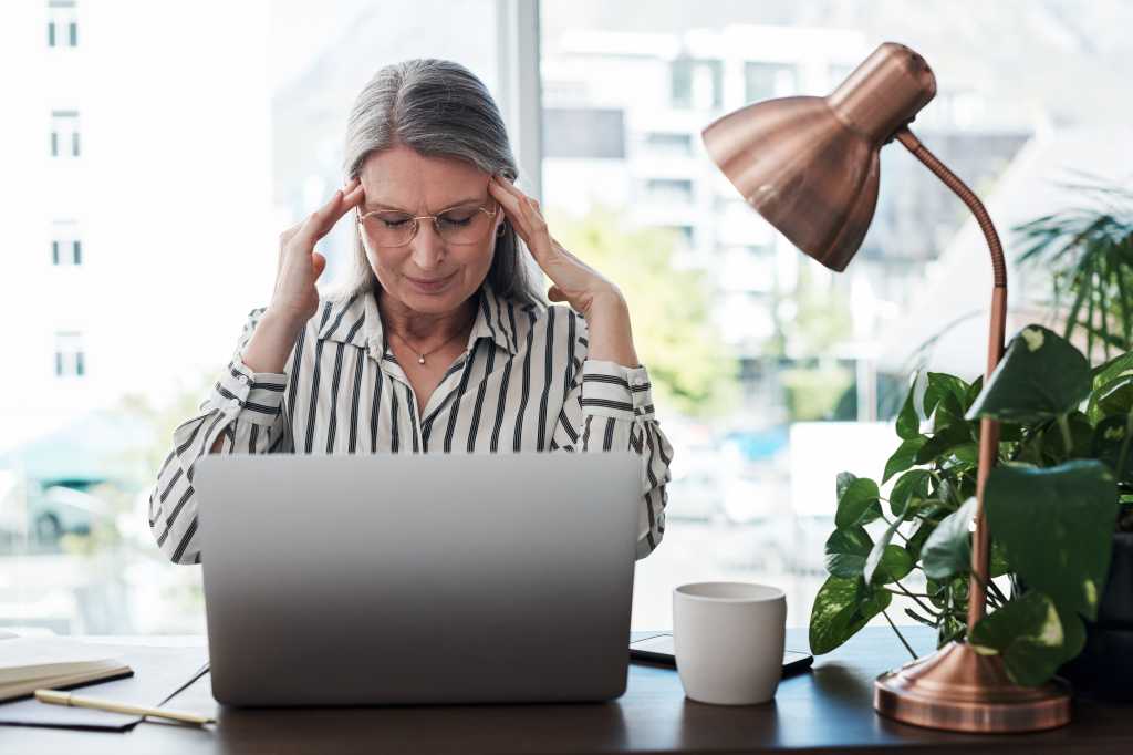 Business woman, headache and stress on computer for deadline, mistake or error of human resource payroll. Mature worker or boss on laptop with migraine, pain or health risk in career, job and office