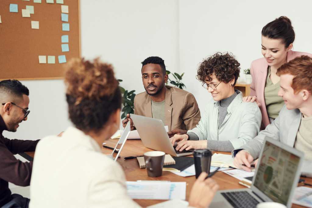 diverse group of employees collaborating at table with laptops